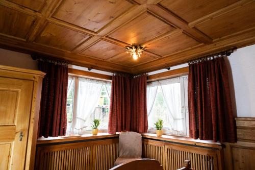 a room with windows with red curtains and a chair at Hotel zum See, Titisee in Titisee-Neustadt