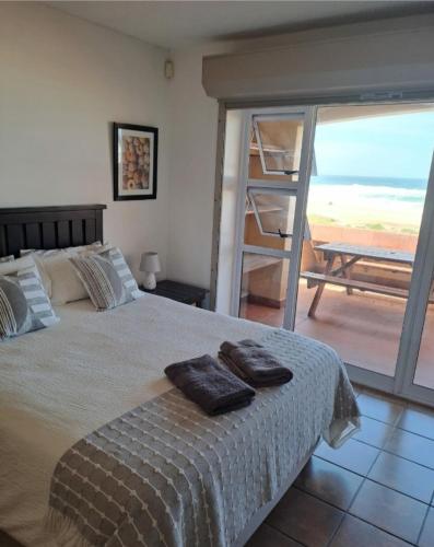 a bedroom with a bed with a view of the ocean at At home on the beach... in Jeffreys Bay