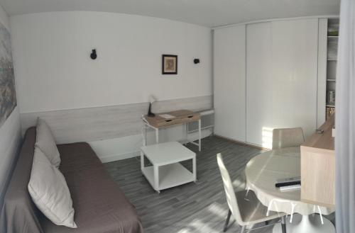 um quarto com um sofá, uma mesa e uma secretária em STUDIO CALME PROCHE CENTRE BORDEAUX em Bordeaux