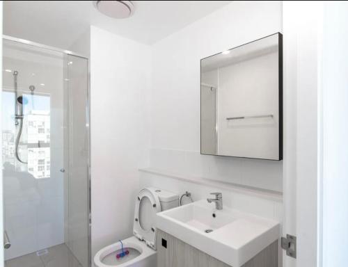 a bathroom with a sink and a toilet and a mirror at Axle x Apartment in Brisbane