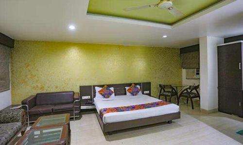 een slaapkamer met een groot bed en een bank bij FabHotel Midland in Bhopal