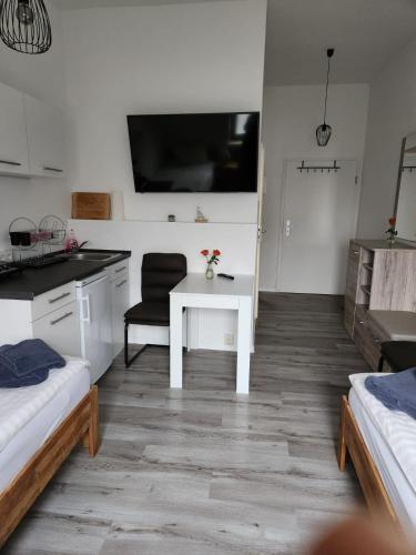 a white kitchen with a white table and a chair at Unterkunft Greifswald in Greifswald