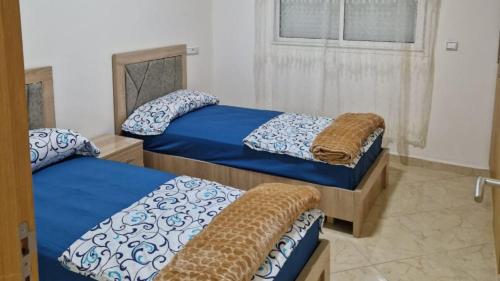 2 camas individuais num quarto com uma janela em Elégant appartement Chez Yalah em Temara