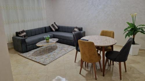 uma sala de estar com um sofá, uma mesa e cadeiras em Elégant appartement Chez Yalah em Temara