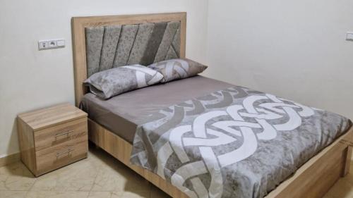 uma cama com uma cabeceira de madeira e uma mesa de cabeceira em Elégant appartement Chez Yalah em Temara