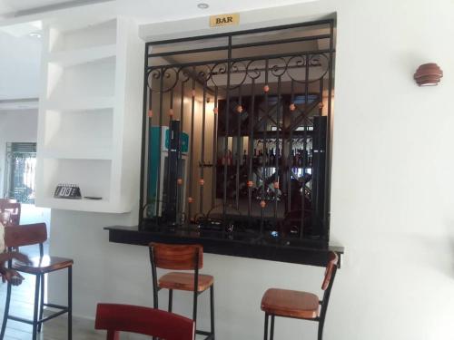 Mbale的住宿－Belmont Villas Mbale，酒吧里摆放着椅子和一束葡萄酒瓶