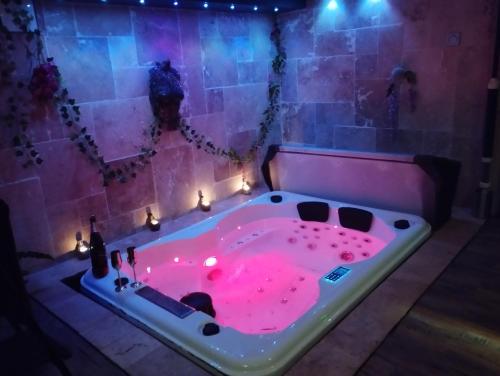 - une baignoire rose avec des lumières dans la chambre dans l'établissement BDC Le Boudoir de Cormelles, à Cormelles