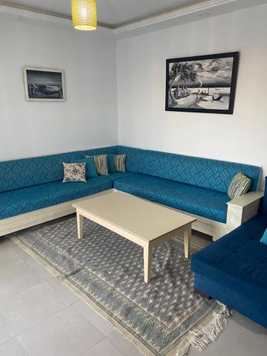 a living room with a blue couch and a coffee table at Duplex El Mansoura A4 in Kelibia
