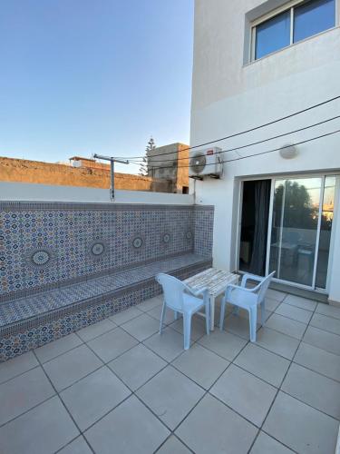 a patio with two chairs and a table on a building at Duplex El Mansoura A4 in Kelibia
