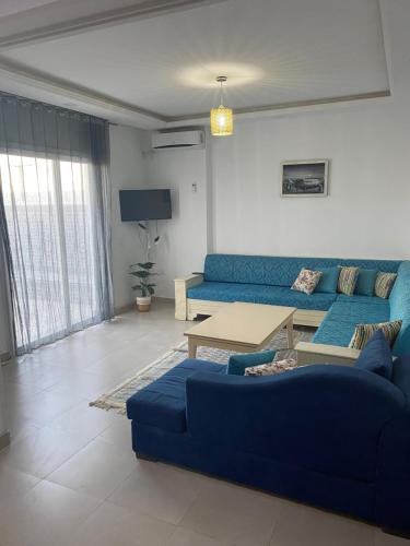 a living room with a blue couch and a table at Duplex El Mansoura A4 in Kelibia