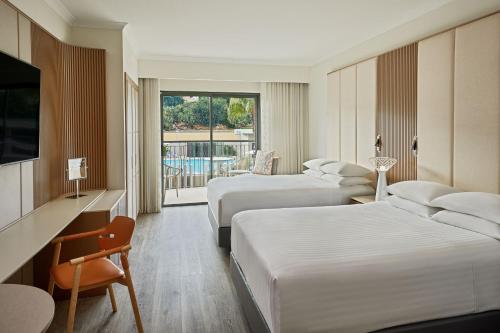 a hotel room with two beds and a television at Malta Marriott Resort & Spa in St. Julianʼs