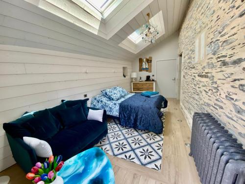 Habitación con sofá, cama y pared de piedra. en Casa Sorriso, en La Daguenière