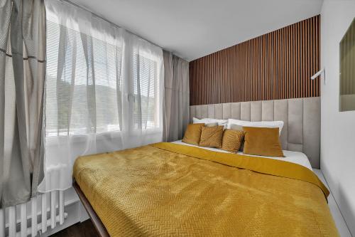 sypialnia z łóżkiem z żółtą pościelą i oknem w obiekcie Apartmán Malina w Swobodzie nad Upą