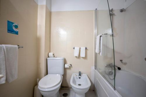 a white bathroom with a toilet and a shower at Hotel Onix in Viseu