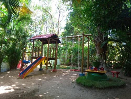um parque infantil com um escorrega e um baloiço em Chalé de Madeira nr03 - Exuberante Flora e Fauna - IMBASSAI em Mata de São João