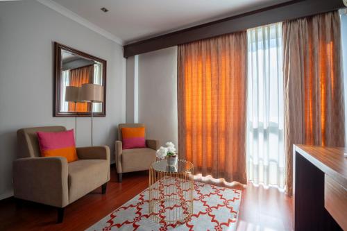 a living room with two chairs and a large window at Hotel Onix in Viseu