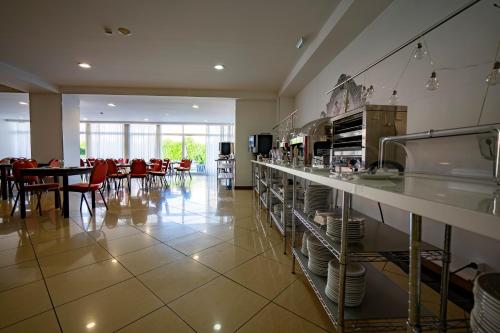 a restaurant with a counter and tables and red chairs at Hotel Onix in Viseu