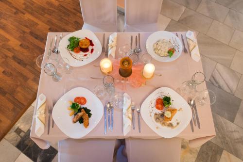 a white table with plates of food on it at Hotel Merkur in Kaluža