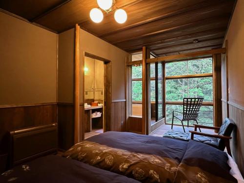 a bedroom with a bed and a window and a chair at Hazu Bekkan in Ono