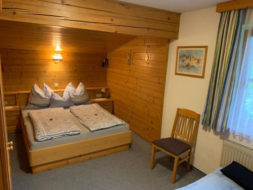 a bedroom with a bed and a chair in a room at Gästehaus ALPINA in Dorfgastein