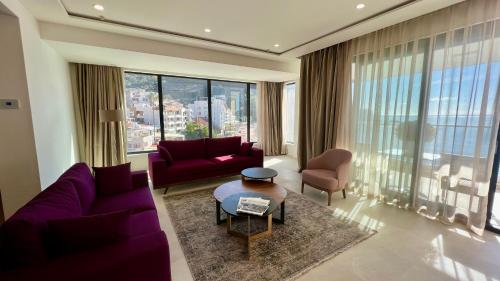 a living room with purple furniture and large windows at Sunraf Luxe Apartments in Budva