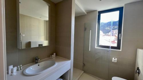 a bathroom with a sink and a mirror and a shower at Sunraf Luxe Apartments in Budva