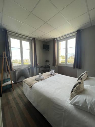 - une chambre avec un grand lit blanc et des fenêtres dans l'établissement Hôtel Le Phare, à Ouistreham