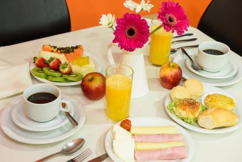 a table topped with plates of food and cups of coffee at Prisma Plaza Hotel in Taubaté