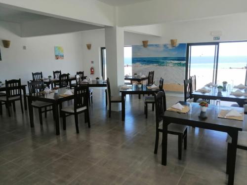 a dining room with tables and chairs and the ocean at Le Marin, Rodrigues Island in Rodrigues Island