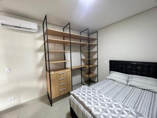 a bedroom with a bed and a book shelf at SoHo Bosque - Studios & Lofts in Presidente Prudente
