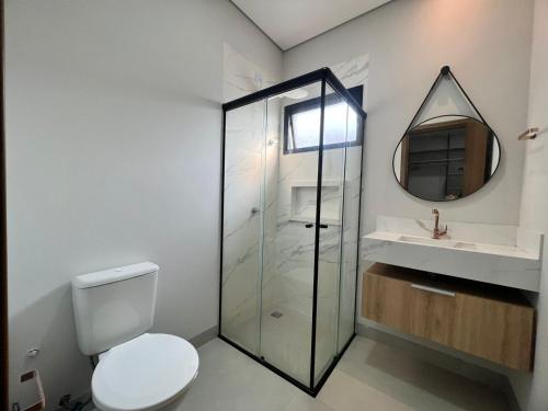 a bathroom with a toilet and a sink and a mirror at SoHo Bosque - Studios & Lofts in Presidente Prudente
