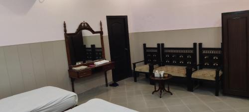 a room with a bed and a table and a mirror at Hotel Shelton Palace in Multan