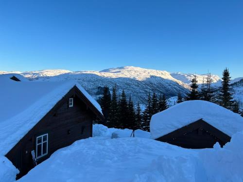 um celeiro coberto de neve com montanhas ao fundo em Hytto em Håra