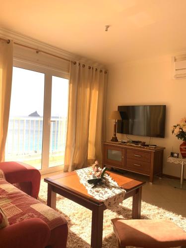 ein Wohnzimmer mit einem TV und einem Couchtisch in der Unterkunft Laginha Beachview in Mindelo
