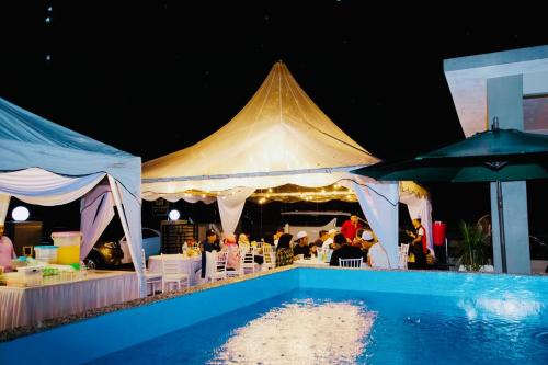 a tent with tables and chairs and a pool at THE PINE HOUSE in Kuala Berang