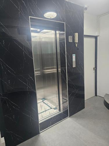 a glass elevator in a room with a black wall at Happy Beach Jomtien Guesthouse in Jomtien Beach
