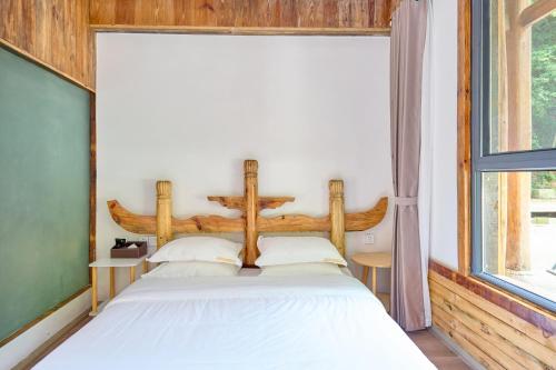 a bed in a room with a large window at Zhumaxi Leisure Lodge in Zhangjiajie