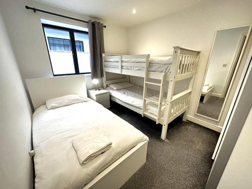 a small bedroom with two bunk beds and a mirror at Daisy Lodge - Spacious Two Bed Flat - Parking, Netflix, WIFI - Close to Blenheim Palace & Oxford - F1 in Kidlington