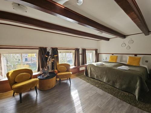 een slaapkamer met een bed en 2 stoelen. bij Hotel Anna Casparii in Harlingen