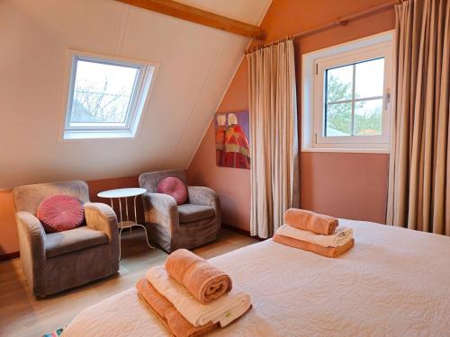 a bedroom with two beds and a chair and windows at Vrijstaand vakantiehuis AK14 Aagtekerke in Aagtekerke