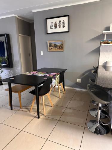 a dining room with a black table and chairs at WeMukelekile (you are welcome) in Lobamba