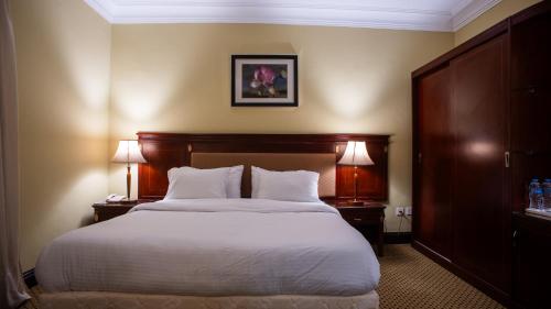 een slaapkamer met een bed met 2 nachtkastjes en 2 lampen bij The Villa 604 Powered by look in Caïro