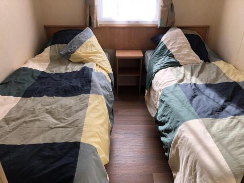 2 camas en un dormitorio pequeño con ventana en chalet, en Kropswolde