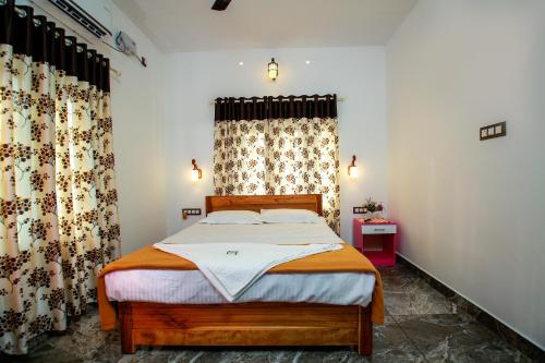 a bedroom with a bed and a window with curtains at BIJIS HOMESTAY in Alleppey