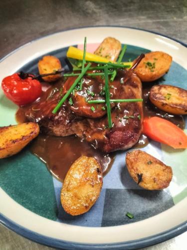 a plate of food with meat and potatoes and carrots at Le Domaine du Terroir à 5 minutes des Grottes de Lascaux in La Chapelle-Aubareil