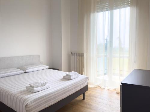 una camera da letto bianca con un letto e asciugamani di Accogliente trilocale a Brescia a Brescia