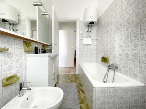 un bagno bianco con vasca e lavandino di Accogliente trilocale a Brescia a Brescia