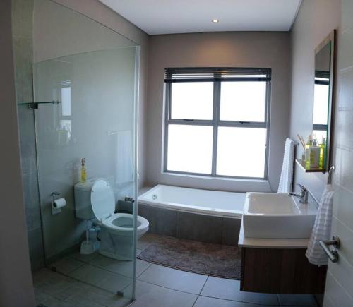 a bathroom with a tub and a toilet and a sink at nile apartment with power backup in Sandton