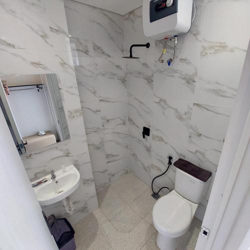 a white bathroom with a toilet and a sink at Rumah Gaharu in Bandung