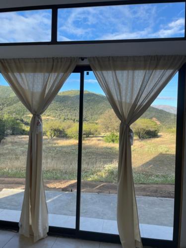 a window with curtains and a view of mountains at Casa los Boldos in Curacaví